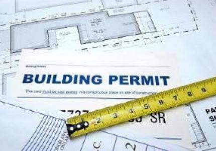 A paper with the title building permit with a measuring tape extended across it