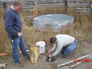 Two men placing a survey instrument into the ground