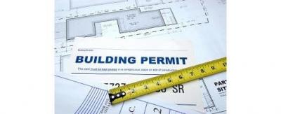 A paper with the title building permit with a measuring tape extended across it
